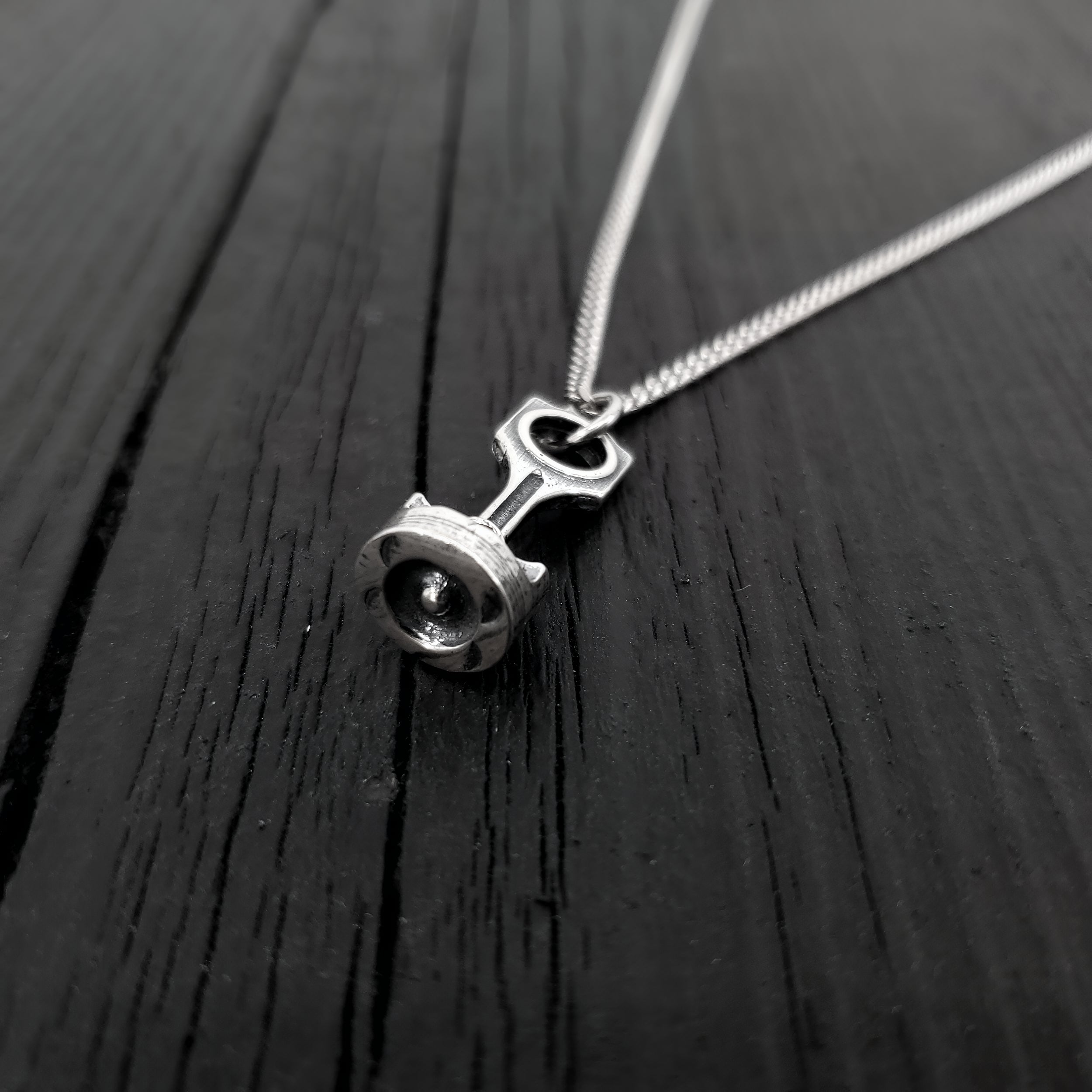 This piston and rod pendant measures 1” Long by 3/8" wide. The precisely detailed 3D rod and piston are cast in one solid piece of sterling silver.