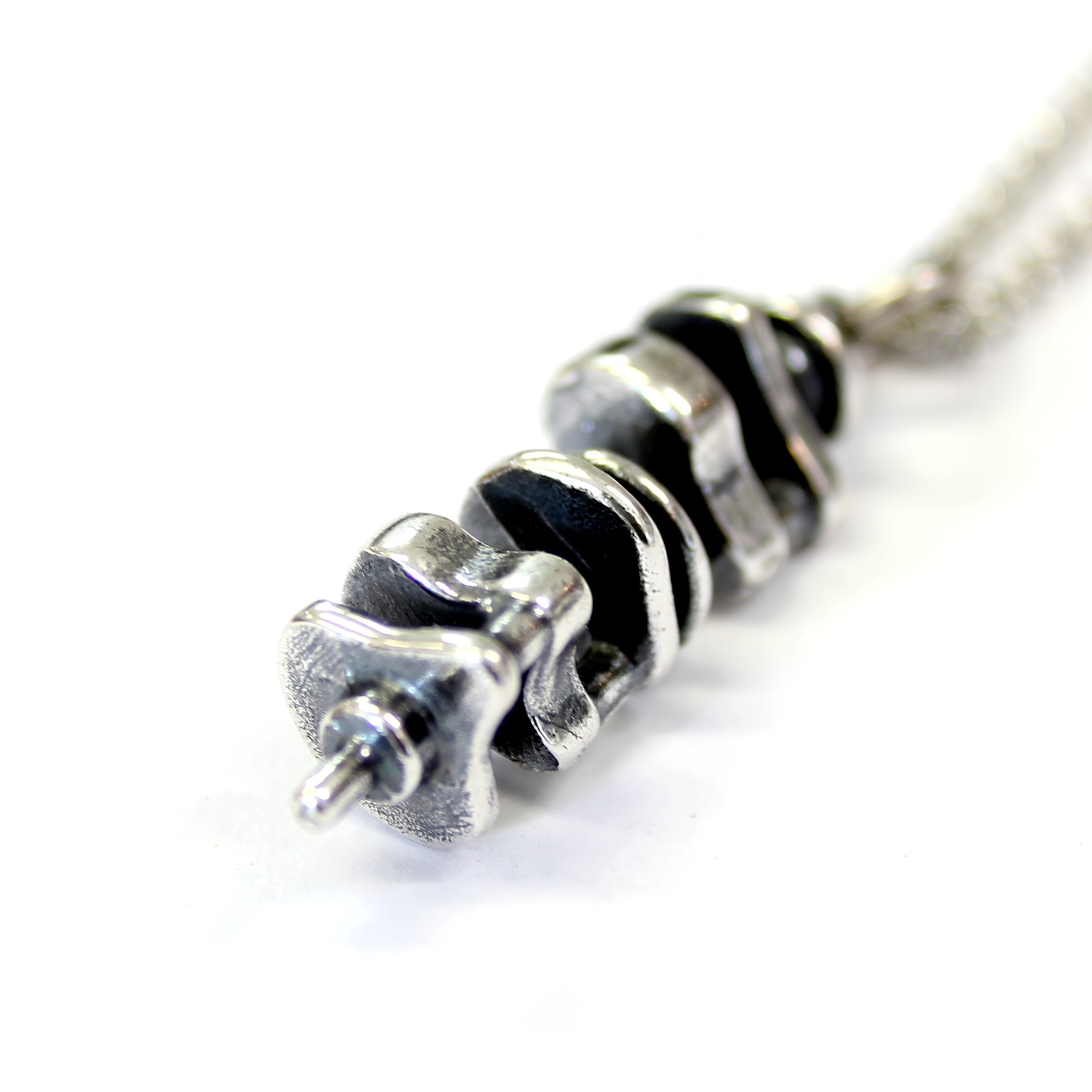 Silver necklace with a black-and-white design on neutral background