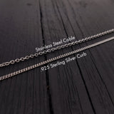 three different types of silver chains laid out on a wooden surface.