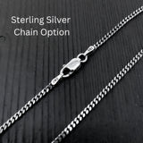 A close-up view of a silver chain necklace with a clasp, resting on a textured surface.